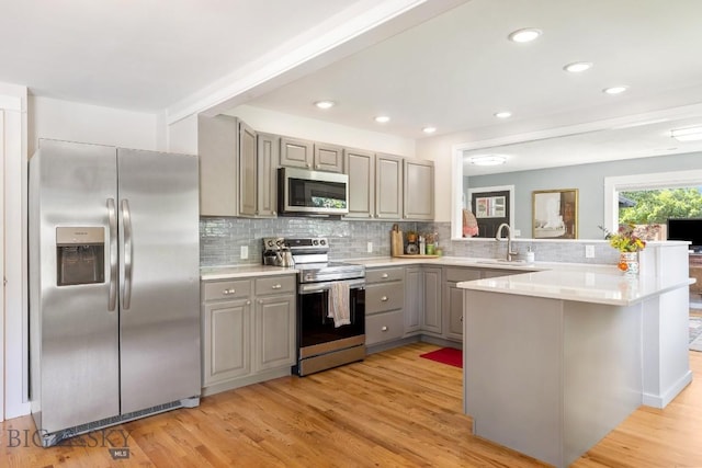 2 Harris Pl, Livingston, MT 59047 - kitchen with appliances with stainless steel finishes, gray cabinetry, a peninsula, decorative backsplash, and light wood-type flooring
