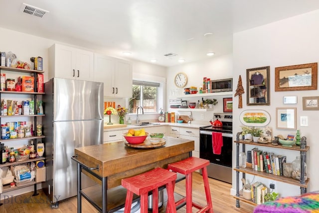 2 Harris Pl, Livingston, MT 59047 - kitchen with appliances with stainless steel finishes, open shelves, white cabinetry, light wood-style flooring, and light countertops