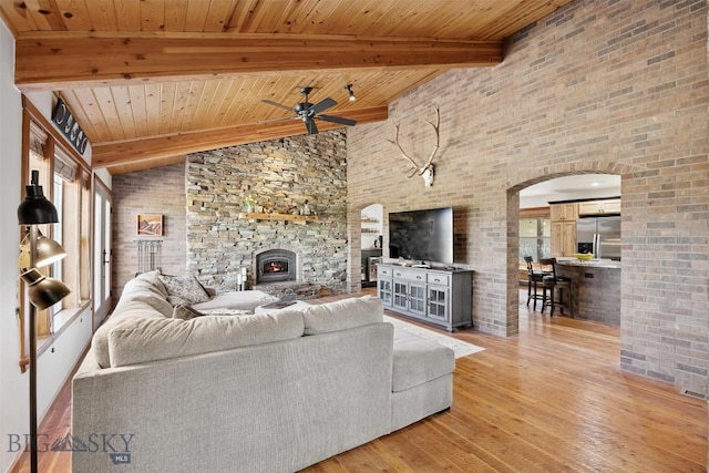 915 Point Of Rocks Rd, Whitehall, MT 59759 - living area featuring a ceiling fan, light wood-style flooring, a wooden ceiling with exposed beams, arched walkways, and a fireplace