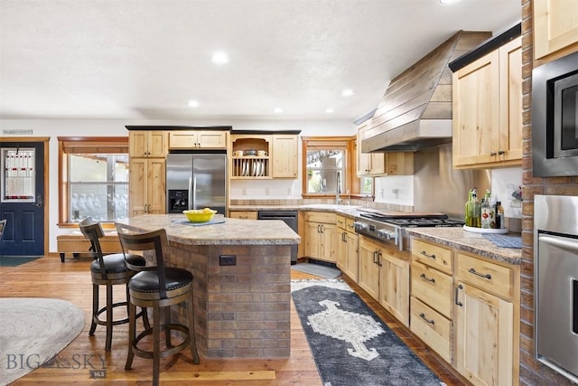 915 Point Of Rocks Rd, Whitehall, MT 59759 - kitchen with stainless steel appliances, light brown cabinetry, wall chimney range hood, healthy amount of natural light, and recessed lighting