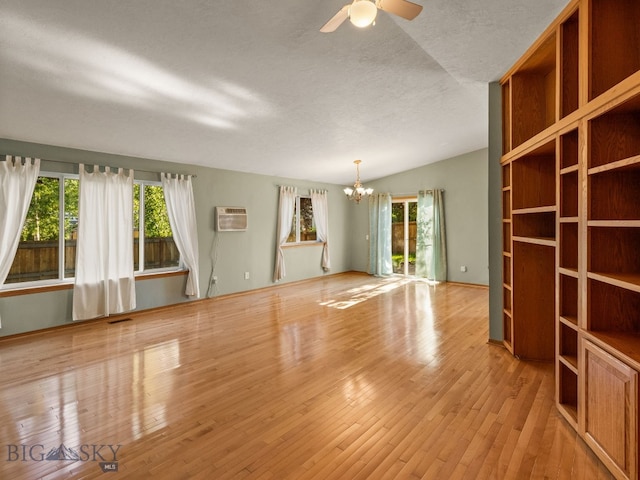 3455 W Cascade, Bozeman, MT 59718 - unfurnished living room featuring a chandelier, plenty of natural light, hardwood / wood-style floors, a wall mounted AC, and a textured ceiling