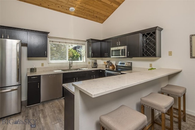 344 Candlelight Meadow Dr, Big Sky, MT 59716 - kitchen with stainless steel appliances, dark cabinetry, wood ceiling, a peninsula, and a breakfast bar area