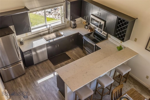 344 Candlelight Meadow Dr, Big Sky, MT 59716 - kitchen featuring appliances with stainless steel finishes, dark wood finished floors, a breakfast bar area, a peninsula, and light stone countertops