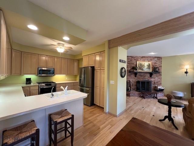 3 Gallatin Unit B, Bozeman, MT 59718 - kitchen featuring stainless steel appliances, a brick fireplace, open floor plan, light countertops, and light wood-style flooring