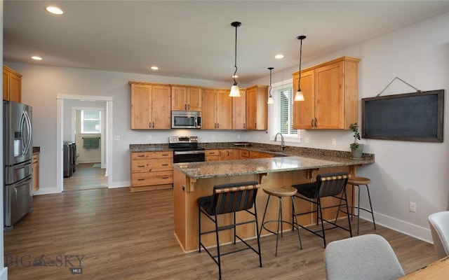3090 Meah Ln, Bozeman, MT 59718 - kitchen with appliances with stainless steel finishes, a peninsula, recessed lighting, a breakfast bar, and wood finished floors