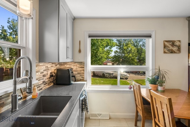 531 N Main St, Livingston, MT 59047 - kitchen featuring backsplash, stainless steel dishwasher, gray cabinetry, and light tile patterned floors