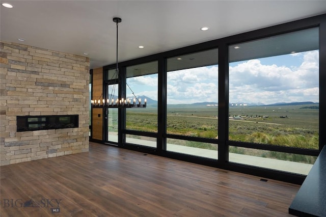 28 Elk Meadows Ranch Rd, Cameron, MT 59720 - unfurnished living room featuring a wall of windows, a fireplace, wood finished floors, a mountain view, and a chandelier