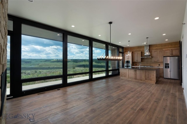 28 Elk Meadows Ranch Rd, Cameron, MT 59720 - kitchen with stainless steel refrigerator with ice dispenser, wall chimney range hood, a center island with sink, floor to ceiling windows, and dark wood-style flooring