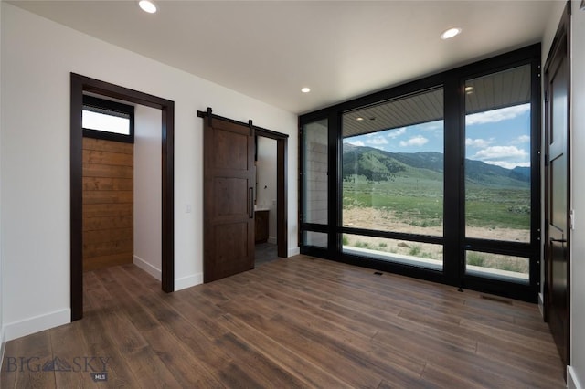 28 Elk Meadows Ranch Rd, Cameron, MT 59720 - unfurnished bedroom with a barn door, multiple windows, dark wood finished floors, a mountain view, and recessed lighting