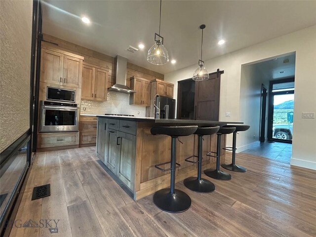 28 Elk Meadows Ranch Rd, Cameron, MT 59720 - kitchen featuring stainless steel oven, wall chimney exhaust hood, fridge with ice dispenser, light wood-style flooring, and black stovetop