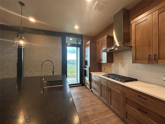 28 Elk Meadows Ranch Rd, Cameron, MT 59720 - kitchen with wall chimney exhaust hood, stainless steel appliances, backsplash, light wood finished floors, and hanging light fixtures