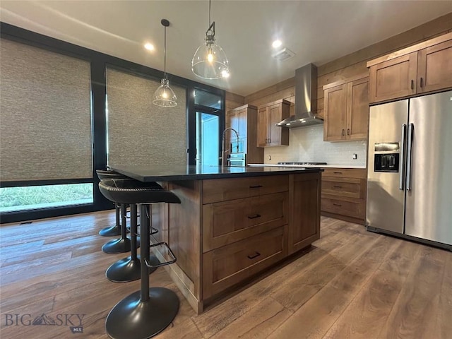 28 Elk Meadows Ranch Rd, Cameron, MT 59720 - kitchen with stainless steel fridge with ice dispenser, wall chimney exhaust hood, wood finished floors, a kitchen breakfast bar, and a center island with sink