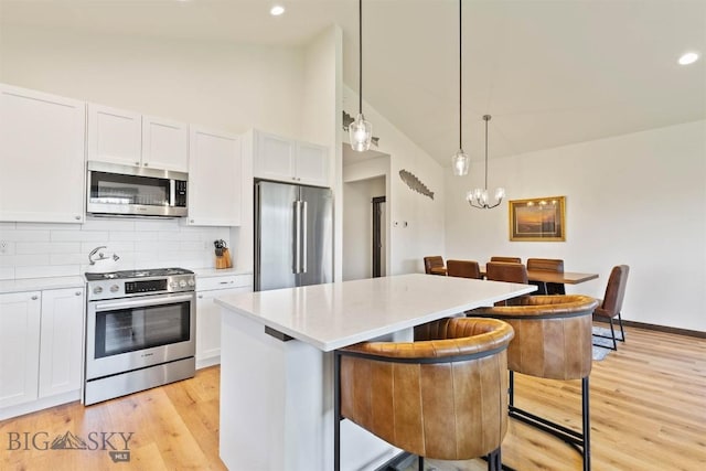 205 Albrey Trl Unit B, Bozeman, MT 59718 - kitchen featuring appliances with stainless steel finishes, white cabinets, a center island, decorative backsplash, and high vaulted ceiling