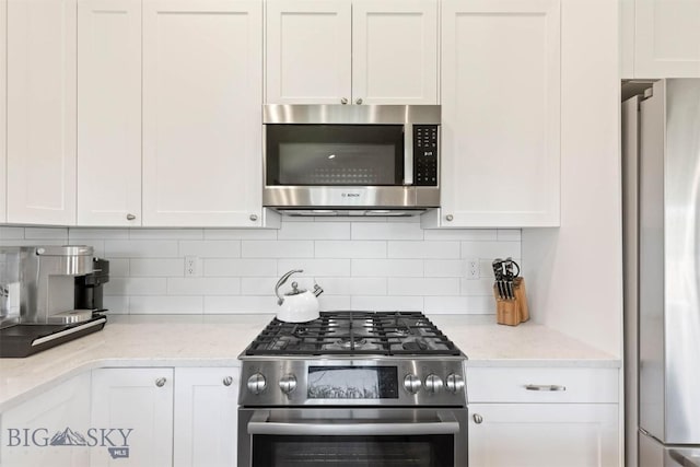 205 Albrey Trl Unit B, Bozeman, MT 59718 - kitchen with stainless steel appliances, white cabinetry, decorative backsplash, and light stone counters