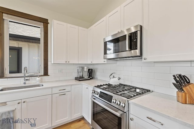 205 Albrey Trl Unit B, Bozeman, MT 59718 - kitchen with appliances with stainless steel finishes, white cabinetry, decorative backsplash, light stone counters, and light wood-style flooring