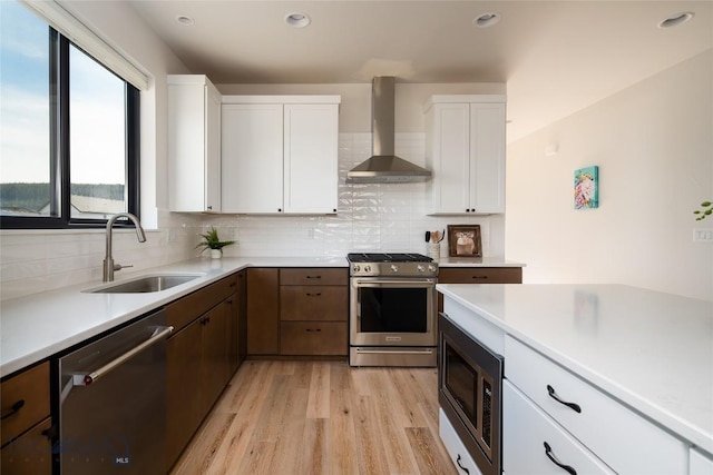 87 Upper Whitefish Dr, Big Sky, MT 59716 - kitchen with appliances with stainless steel finishes, wall chimney exhaust hood, light countertops, light wood finished floors, and backsplash