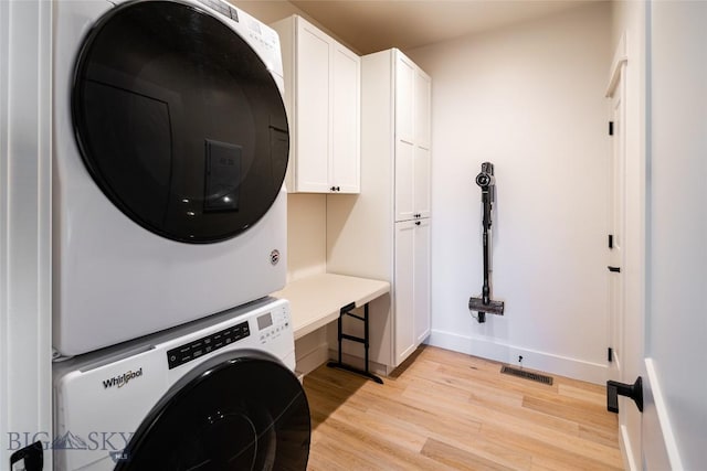 87 Upper Whitefish Dr, Big Sky, MT 59716 - laundry area with stacked washing machine and dryer, cabinet space, and light wood-style flooring