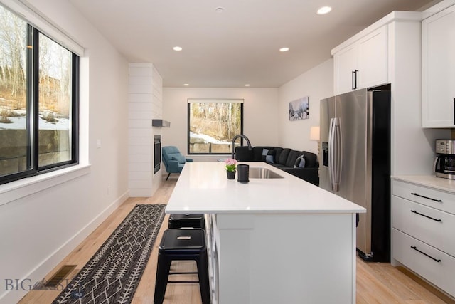 87 Upper Whitefish Dr, Big Sky, MT 59716 - kitchen with stainless steel fridge, light wood-style floors, open floor plan, a kitchen island with sink, and light countertops