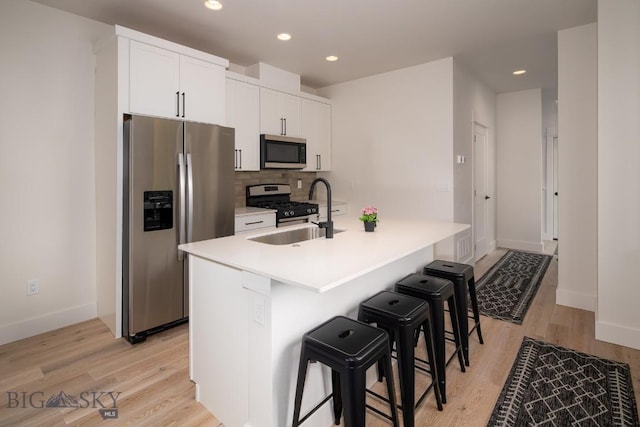 87 Upper Whitefish Dr, Big Sky, MT 59716 - kitchen featuring appliances with stainless steel finishes, a kitchen bar, light wood finished floors, white cabinets, and tasteful backsplash