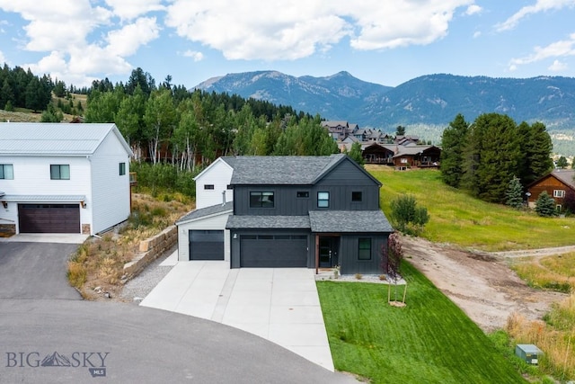 87 Upper Whitefish Dr, Big Sky, MT 59716 - view of front of property featuring board and batten siding, concrete driveway, a mountain view, a front lawn, and a garage