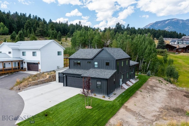 87 Upper Whitefish Dr, Big Sky, MT 59716 - view of front facade featuring board and batten siding, driveway, an attached garage, a front yard, and a mountain view