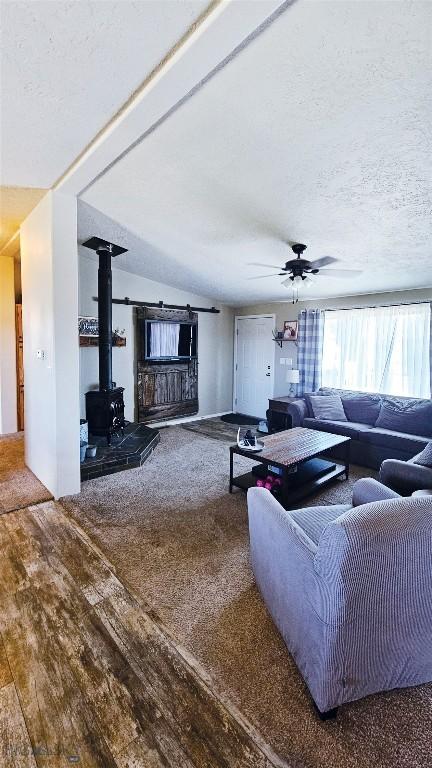 950 N Harrison St, Lima, MT 59739 - living room featuring a wood stove, hardwood / wood-style flooring, ceiling fan, and a textured ceiling
