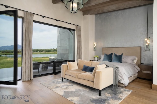 240 Horsetail Rd, Bozeman, MT 59715 - bedroom featuring wood finished floors, access to exterior, a water view, multiple windows, and beam ceiling