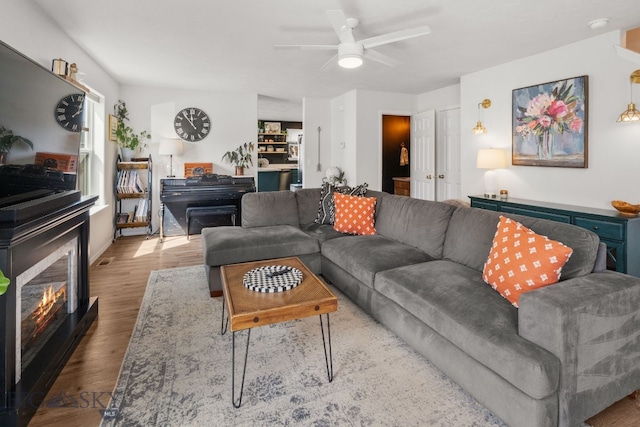 119 Meadow Brook Ln, Belgrade, MT 59714 - living room featuring wood finished floors, a ceiling fan, and a glass covered fireplace