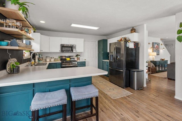 119 Meadow Brook Ln, Belgrade, MT 59714 - kitchen featuring stainless steel appliances, open shelves, a peninsula, light wood-style floors, and light countertops