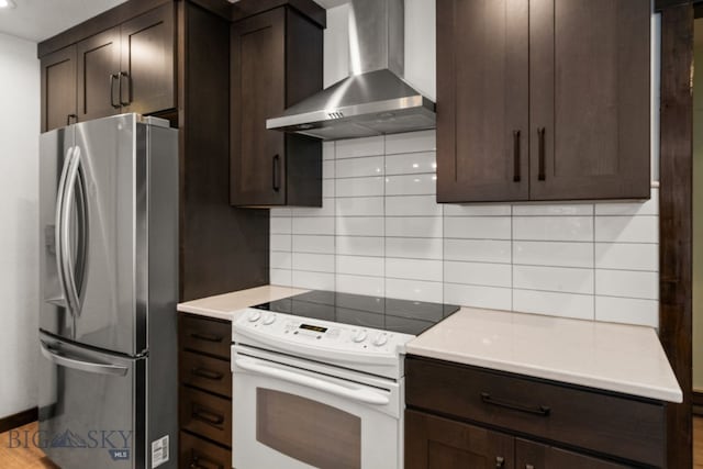 840 Damarell Rd, Bozeman, MT 59718 - kitchen with wall chimney range hood, freestanding refrigerator, electric range, and dark brown cabinetry