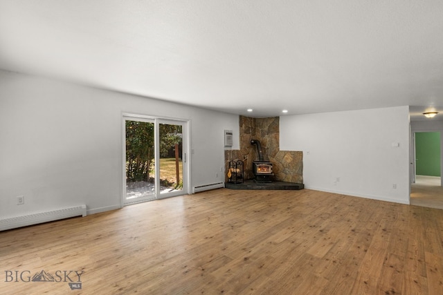 840 Damarell Rd, Bozeman, MT 59718 - unfurnished living room with a wood stove, a baseboard heating unit, wood finished floors, recessed lighting, and a wall unit AC