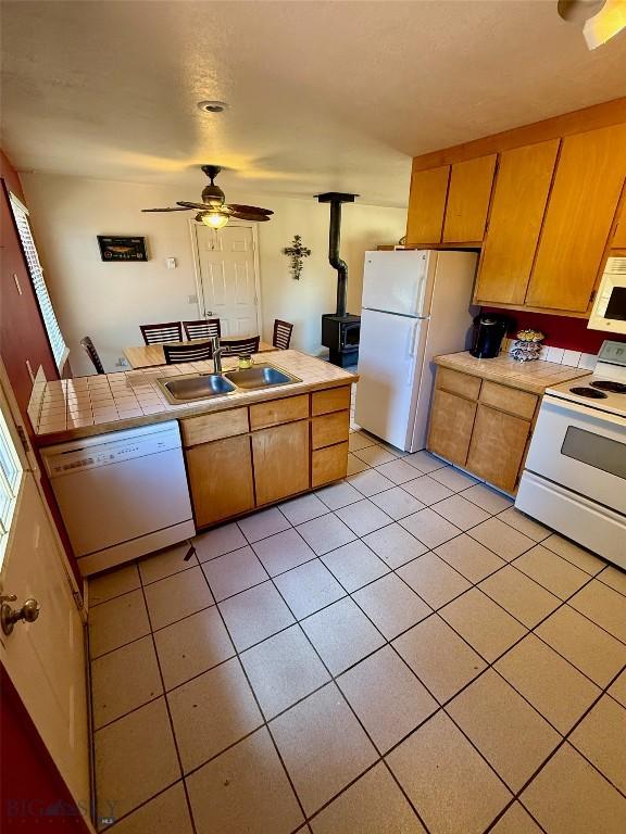 1364 Mcclellan Rd, West Yellowstone, MT 59758 - kitchen with white appliances, a wood stove, a ceiling fan, light tile patterned floors, and tile countertops