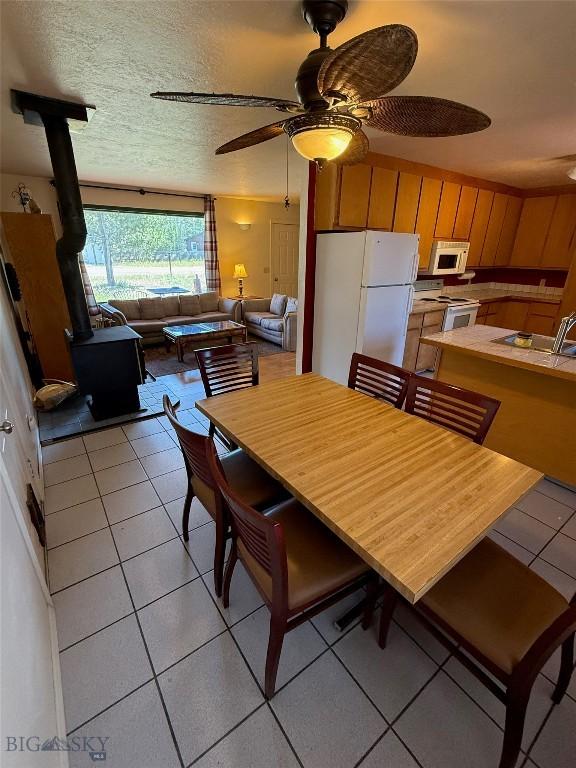 1364 Mcclellan Rd, West Yellowstone, MT 59758 - dining area featuring a wood stove, light tile patterned flooring, and a ceiling fan