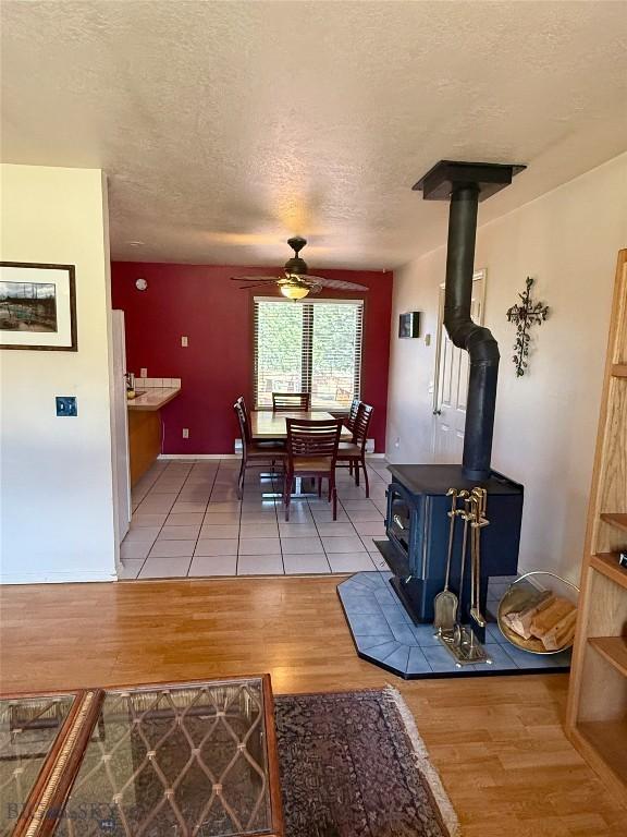 1364 Mcclellan Rd, West Yellowstone, MT 59758 - dining space featuring a ceiling fan, light wood-style flooring, a textured ceiling, and a wood stove