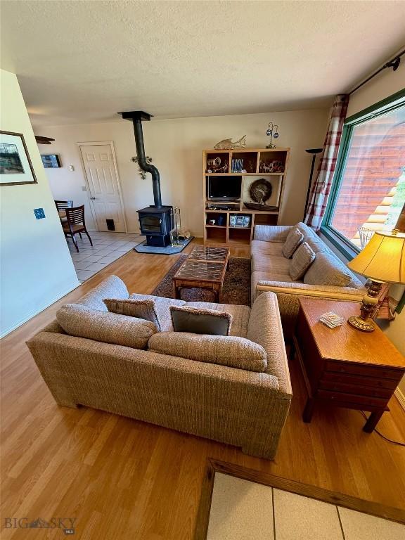 1364 Mcclellan Rd, West Yellowstone, MT 59758 - living room featuring a wood stove, wood finished floors, and a textured ceiling