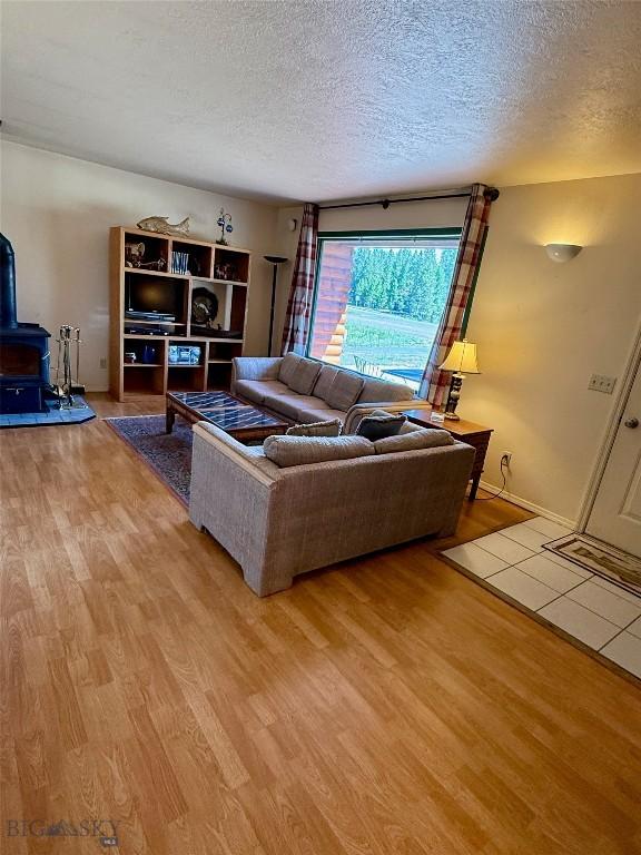 1364 Mcclellan Rd, West Yellowstone, MT 59758 - living room featuring a textured ceiling, a wood stove, and wood finished floors