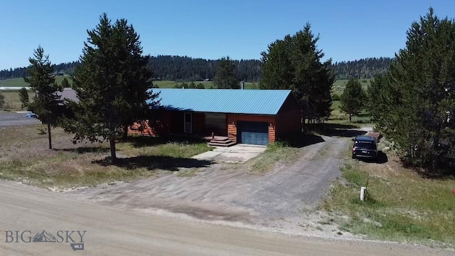 1364 Mcclellan Rd, West Yellowstone, MT 59758 - view of front of home with a garage, driveway, a view of trees, and a metal roof