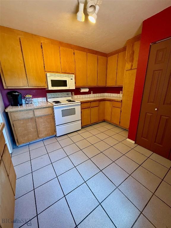 1364 Mcclellan Rd, West Yellowstone, MT 59758 - kitchen featuring white appliances, light tile patterned flooring, and light countertops