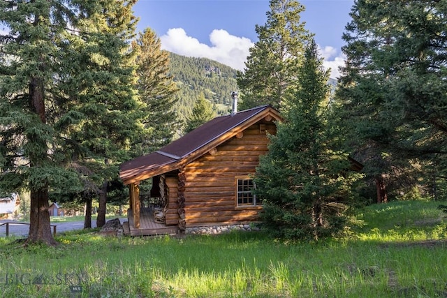 49824 Gallatin Rd, Big Sky, MT 59730 - view of side of home with log siding, a wooded view, and a metal roof