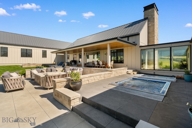 1878 Star Ridge Rd, Bozeman, MT 59715 - rear view of property featuring a patio, board and batten siding, a chimney, an in-ground hot tub, and a metal roof