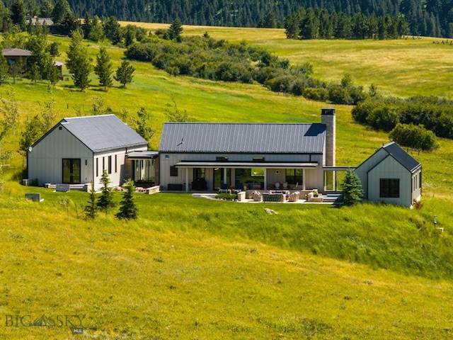1878 Star Ridge Rd, Bozeman, MT 59715 - back of property with a chimney, a patio, a metal roof, a lawn, and a wooded view