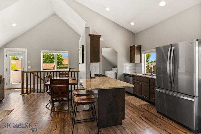 3139 Blackbird Dr, Bozeman, MT 59718 - kitchen featuring stainless steel appliances, separate washer and dryer, dark brown cabinetry, dark wood-style floors, and light stone countertops