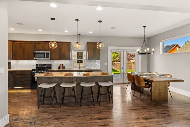 3139 Blackbird Dr, Bozeman, MT 59718 - kitchen featuring stainless steel microwave, black range with gas stovetop, decorative backsplash, a center island, and a breakfast bar
