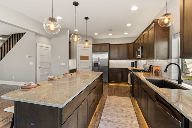 3139 Blackbird Dr, Bozeman, MT 59718 - kitchen with appliances with stainless steel finishes, wood finished floors, a kitchen island, tasteful backsplash, and dark brown cabinets