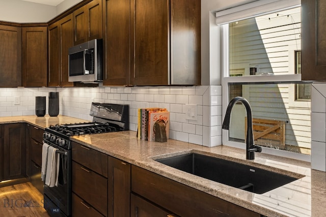 3139 Blackbird Dr, Bozeman, MT 59718 - kitchen with black range with gas stovetop, stainless steel microwave, light stone countertops, and dark brown cabinets