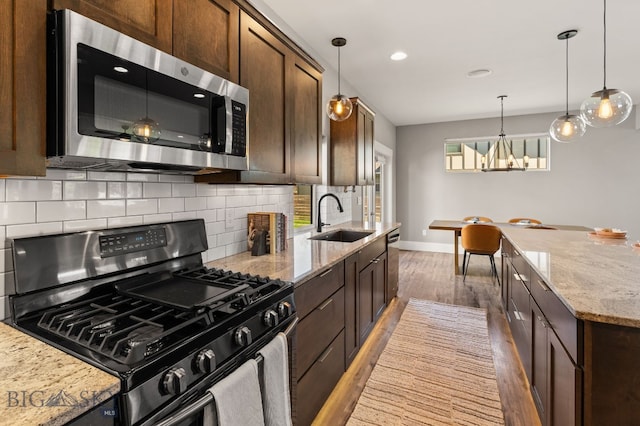 3139 Blackbird Dr, Bozeman, MT 59718 - kitchen with appliances with stainless steel finishes, backsplash, a chandelier, wood finished floors, and light stone countertops