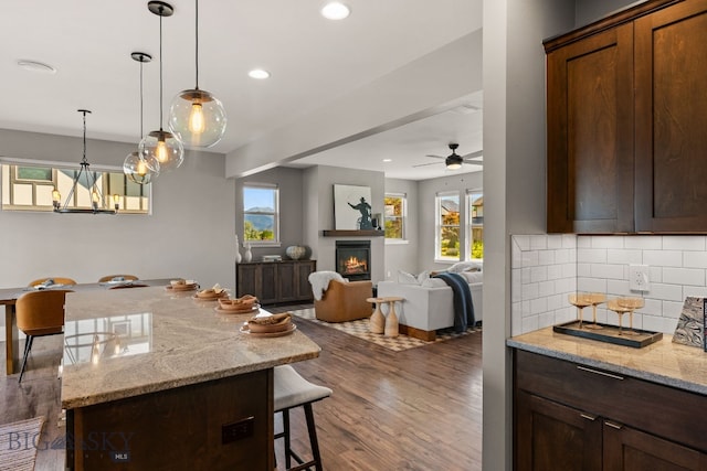 3139 Blackbird Dr, Bozeman, MT 59718 - kitchen featuring a glass covered fireplace, a kitchen breakfast bar, dark wood-style floors, tasteful backsplash, and recessed lighting