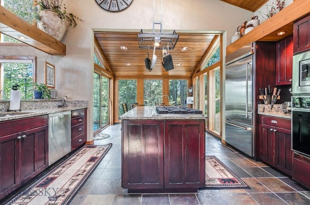953 Angel Point Rd, Lakeside, MT 59922 - kitchen with built in appliances, vaulted ceiling, reddish brown cabinets, wood ceiling, and stone tile floors