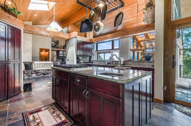 953 Angel Point Rd, Lakeside, MT 59922 - kitchen featuring stone tile flooring, wooden ceiling, healthy amount of natural light, an island with sink, and dark stone counters