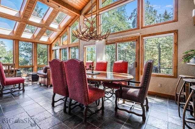 953 Angel Point Rd, Lakeside, MT 59922 - dining area with a textured wall, stone tile floors, high vaulted ceiling, a skylight, and a chandelier
